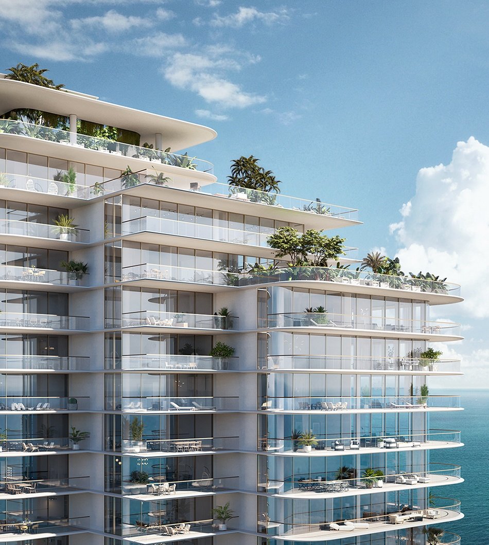 Modern multi-story glass building with balconies, some with outdoor furniture and plants, overlooking the ocean under a partly cloudy sky.