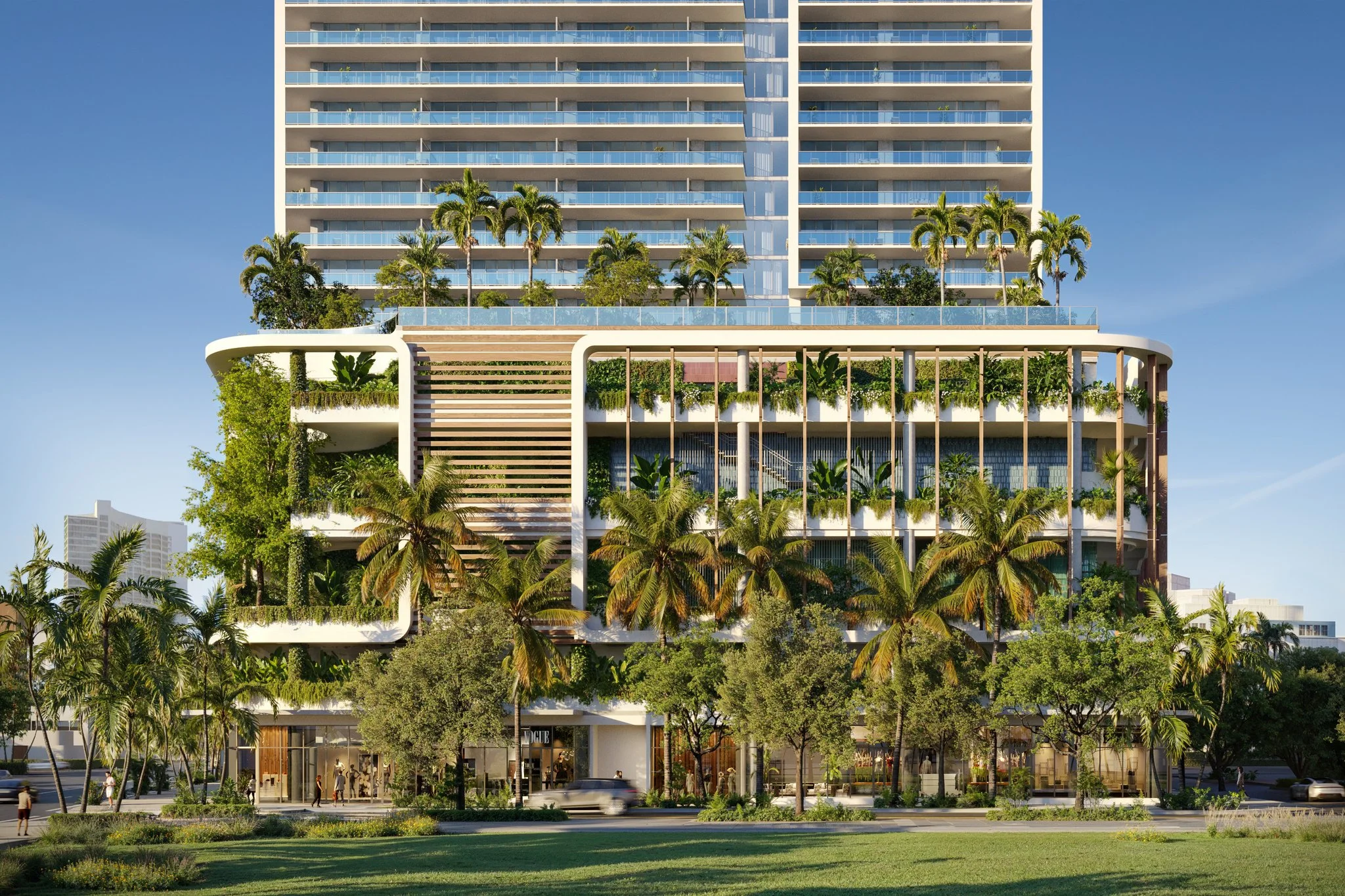 Modern multi-story building with commercial spaces on the ground floor and residential or office spaces above. The building features extensive greenery, with palm trees and plants on balconies and terraces. The lower part has large glass windows and a few people walking nearby.