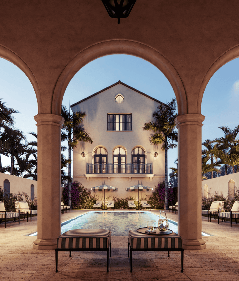 Luxurious backyard with a swimming pool, surrounded by palm trees and outdoor chairs, viewed from an arched patio with a two-story house in the background