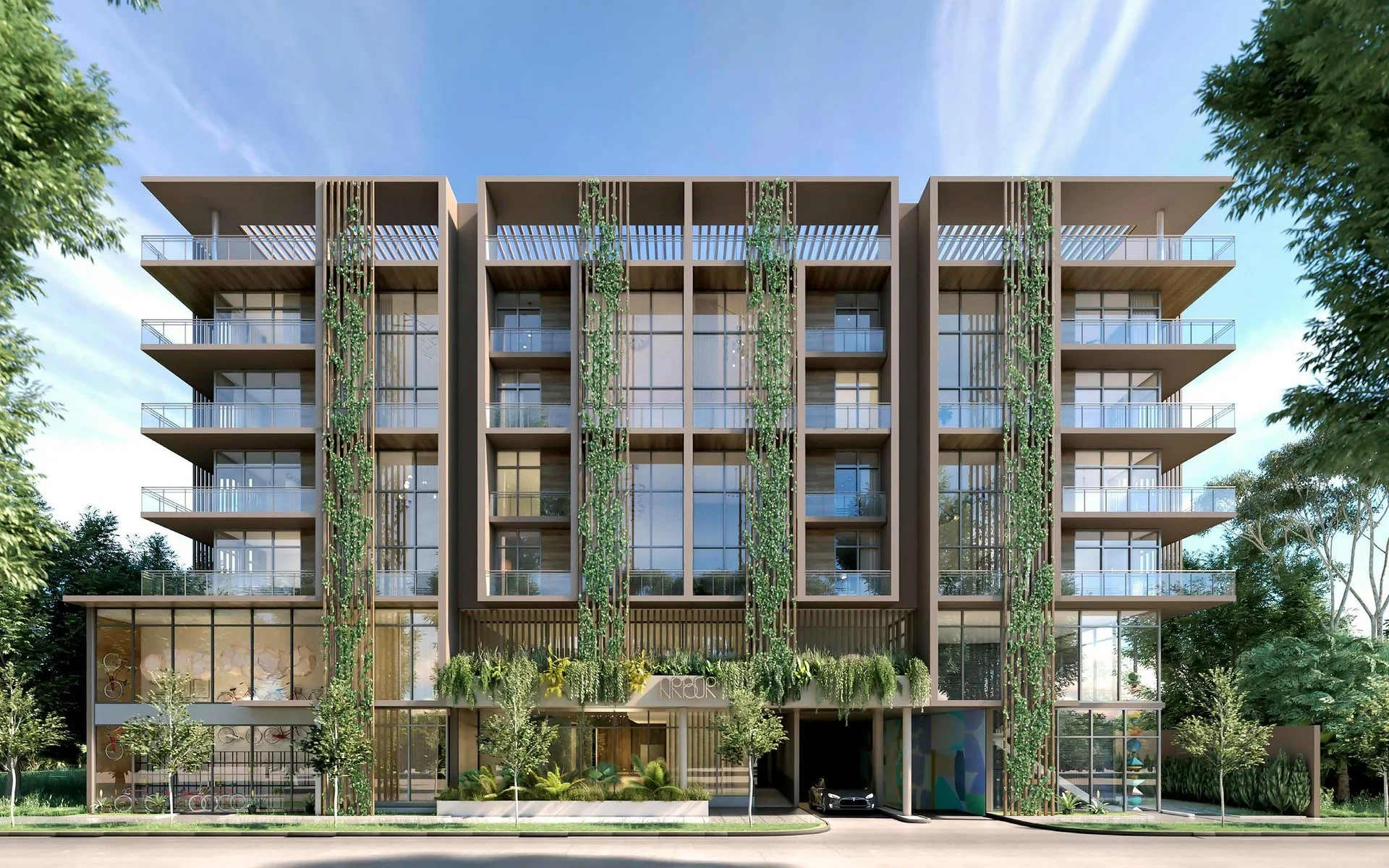 Modern multi-story residential building with balconies and green vertical gardens, surrounded by trees and a clear sky.