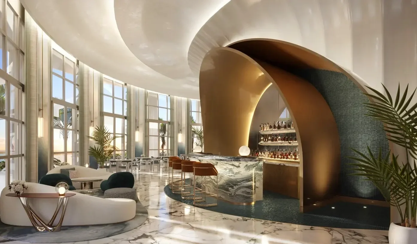 Luxurious hotel lobby with marble floors, modern bar with gold accents, and large windows letting in natural light.