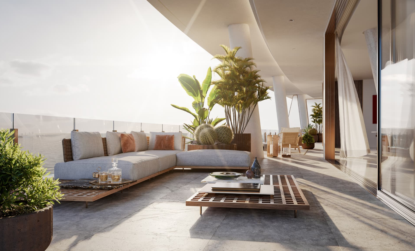 Modern outdoor balcony with a large sectional sofa, potted plants, a coffee table with decorative objects, and a view of the city skyline at sunset.