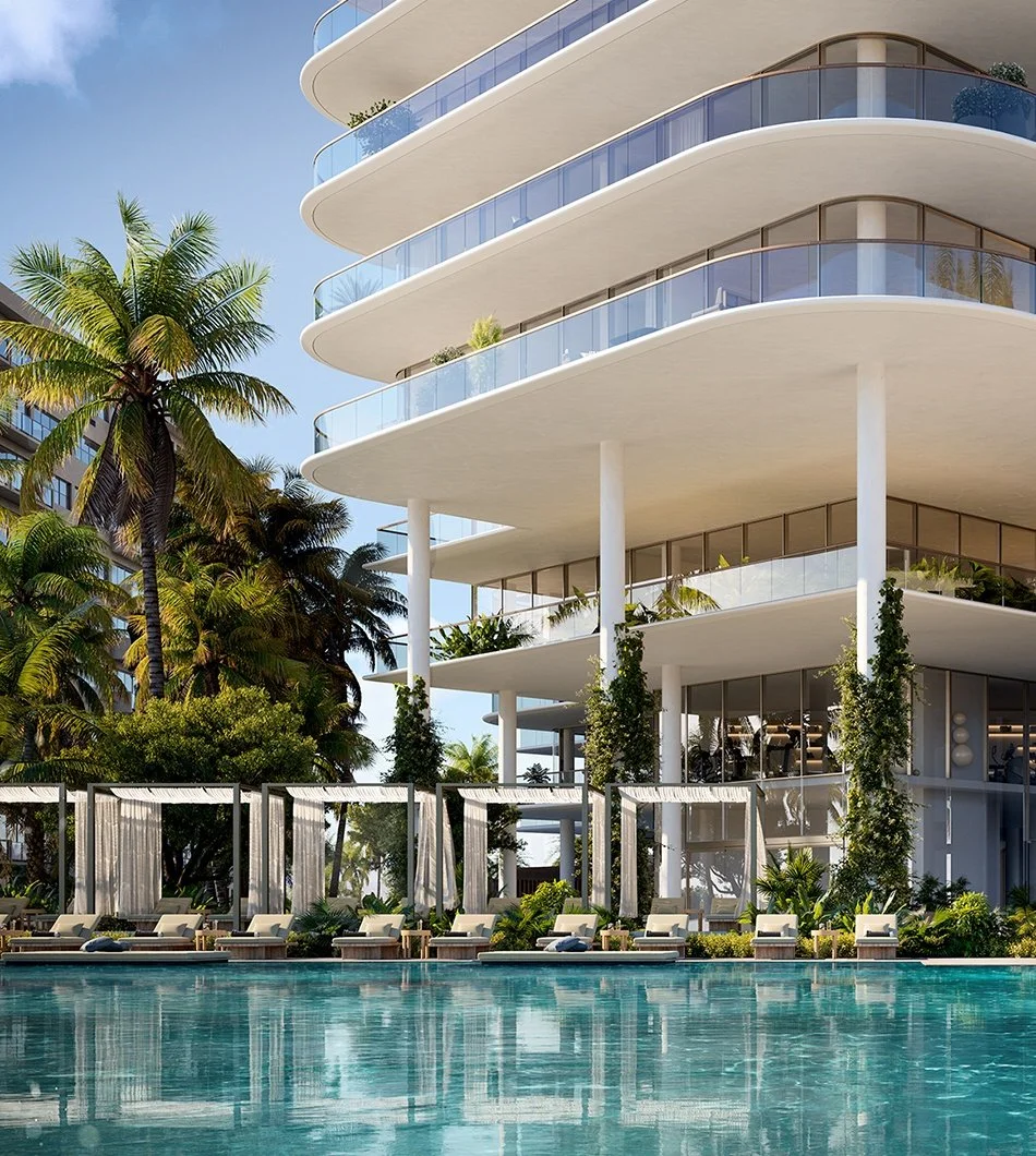 Modern white hotel building with curved balconies, surrounded by palm trees, with poolside loungers and cabanas in the foreground.