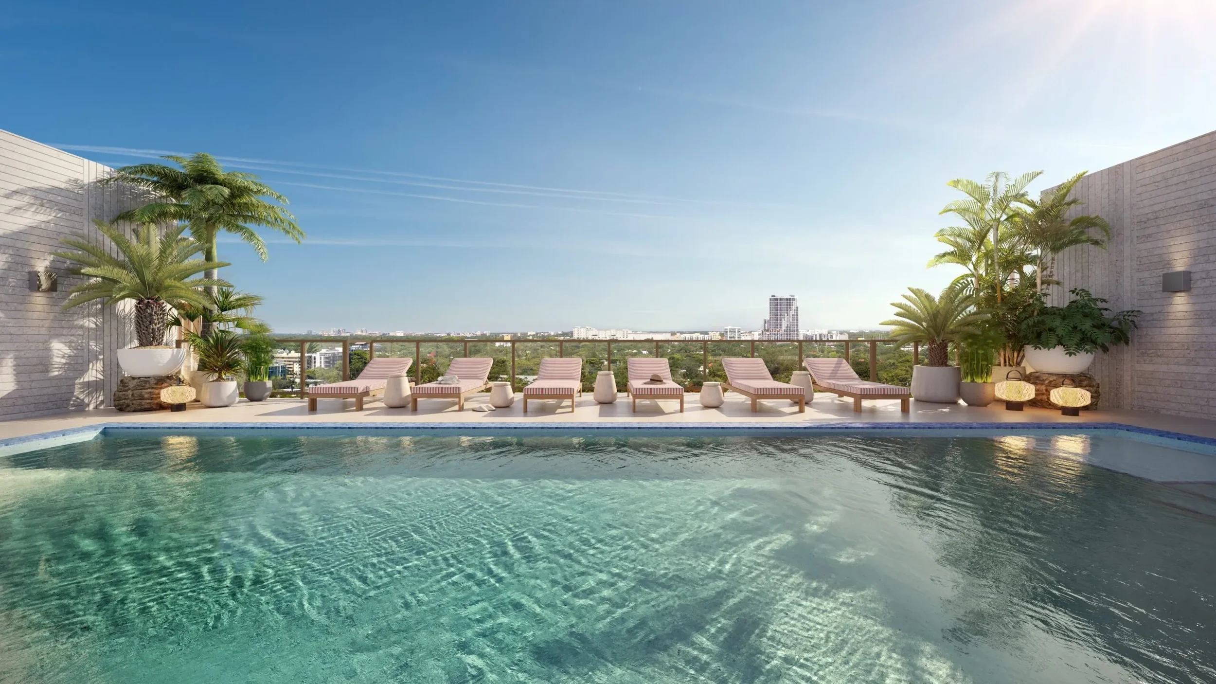 Rooftop pool with lounge chairs, potted plants, and city view in the background under a clear blue sky.
