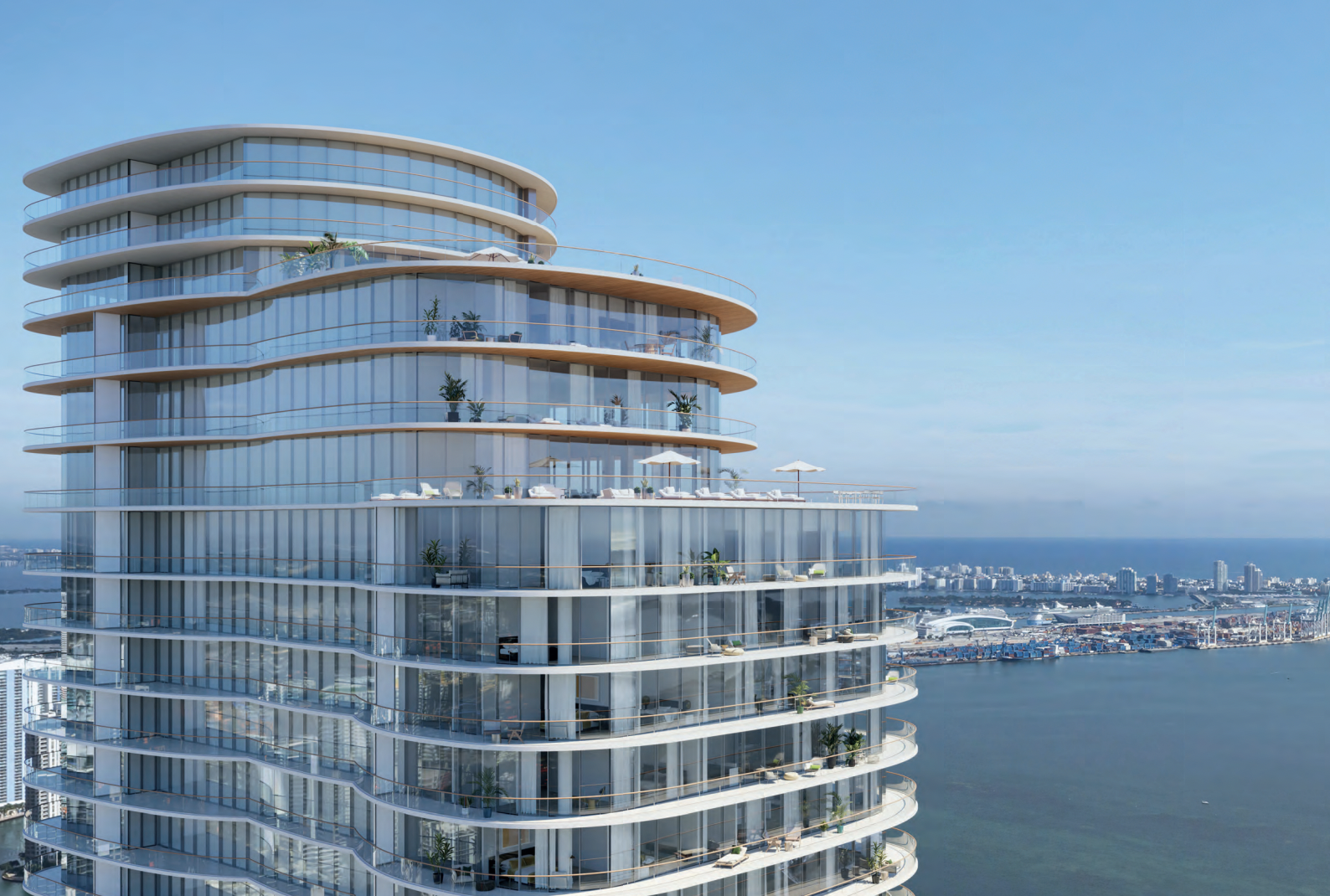 A modern high-rise building with curved glass balconies overlooking a body of water and a cityscape in the background.