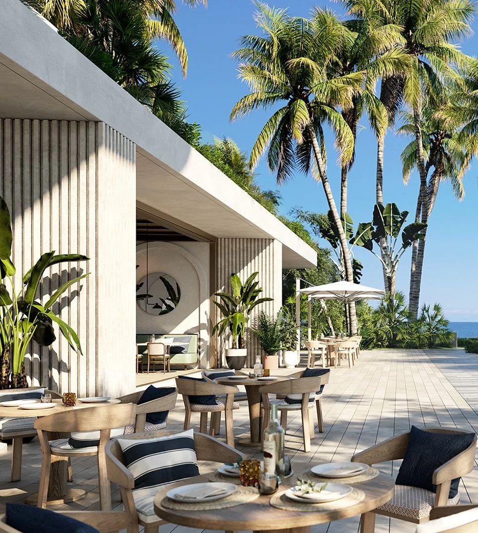 Outdoor patio of a modern beachfront restaurant or home, with wooden tables and chairs, tropical plants, and tall palm trees under a clear blue sky, with the ocean visible in the distance.