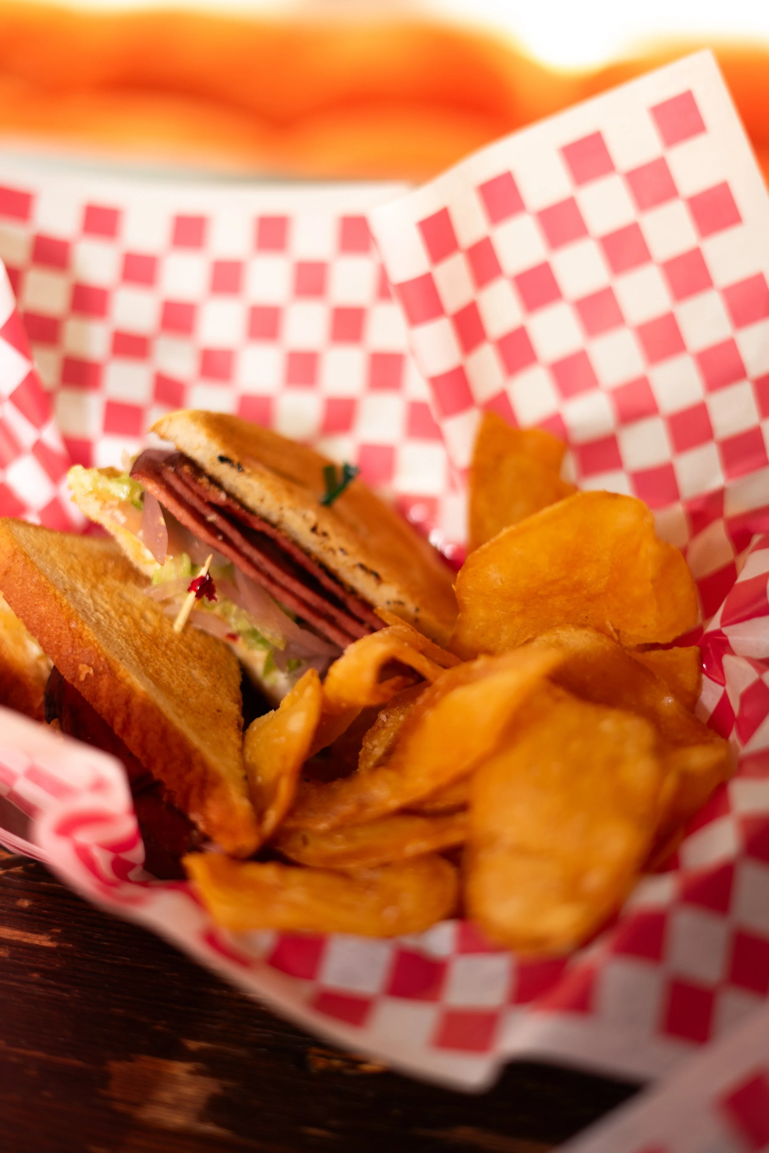 Sandwich and chips against a red and white checkered backdrop.