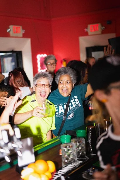 Two people smiling and watching a game at Marsha's.