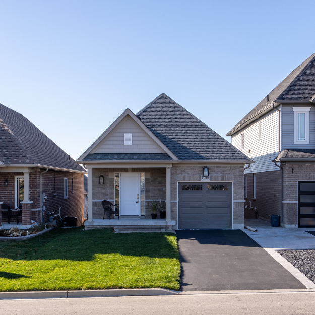 Front view of a modern house with a small porch, garage, and well-maintained lawn in a neighborhood.