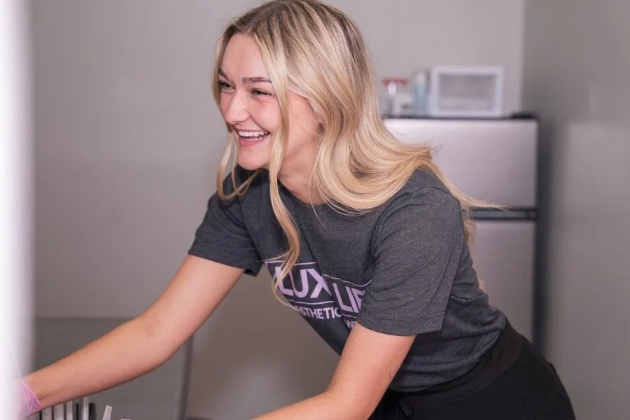 A young woman with blonde hair smiling while doing laundry in a laundry room.