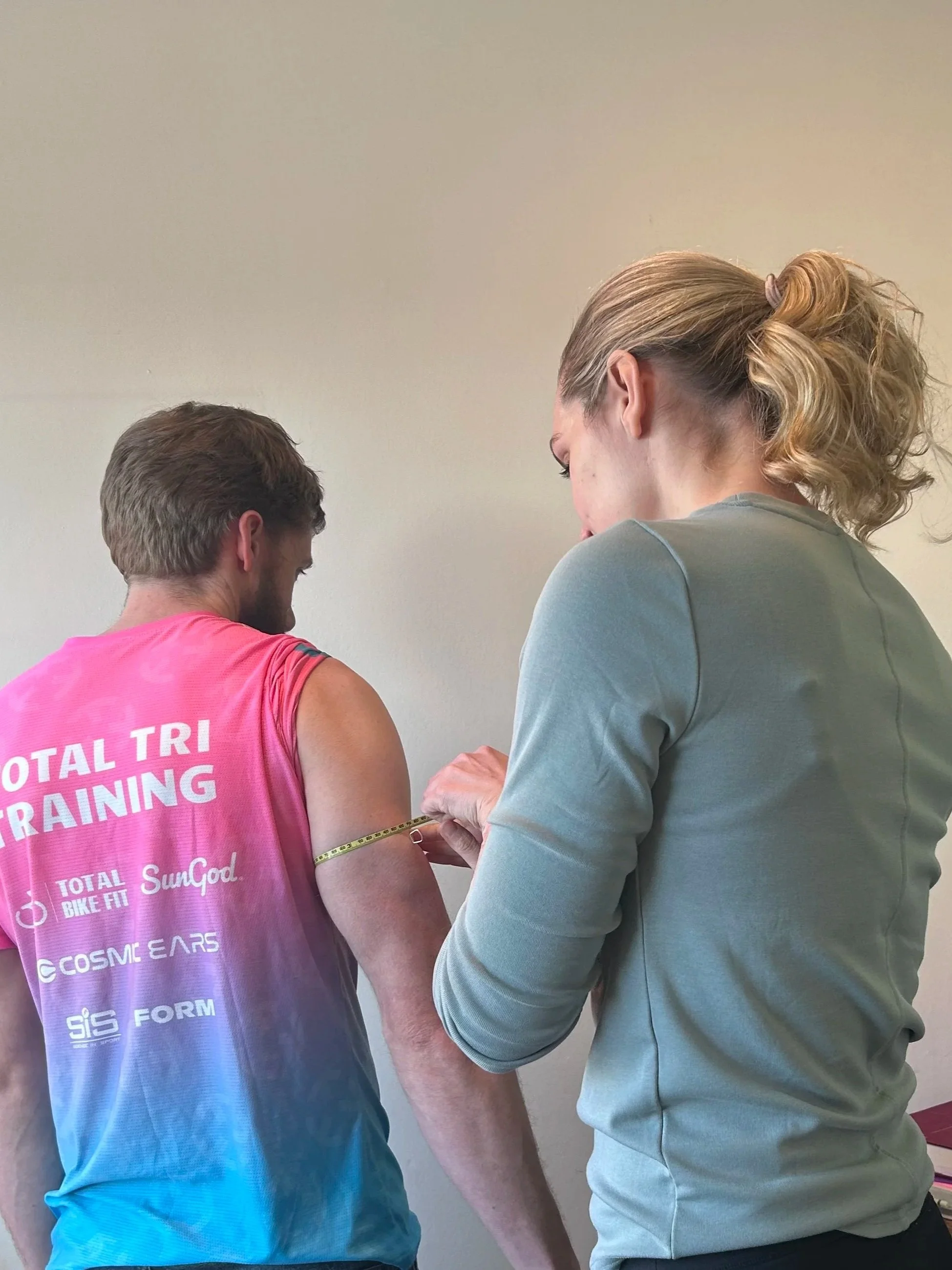 Sports nutritionist taking mid-arm circumference from an athlete