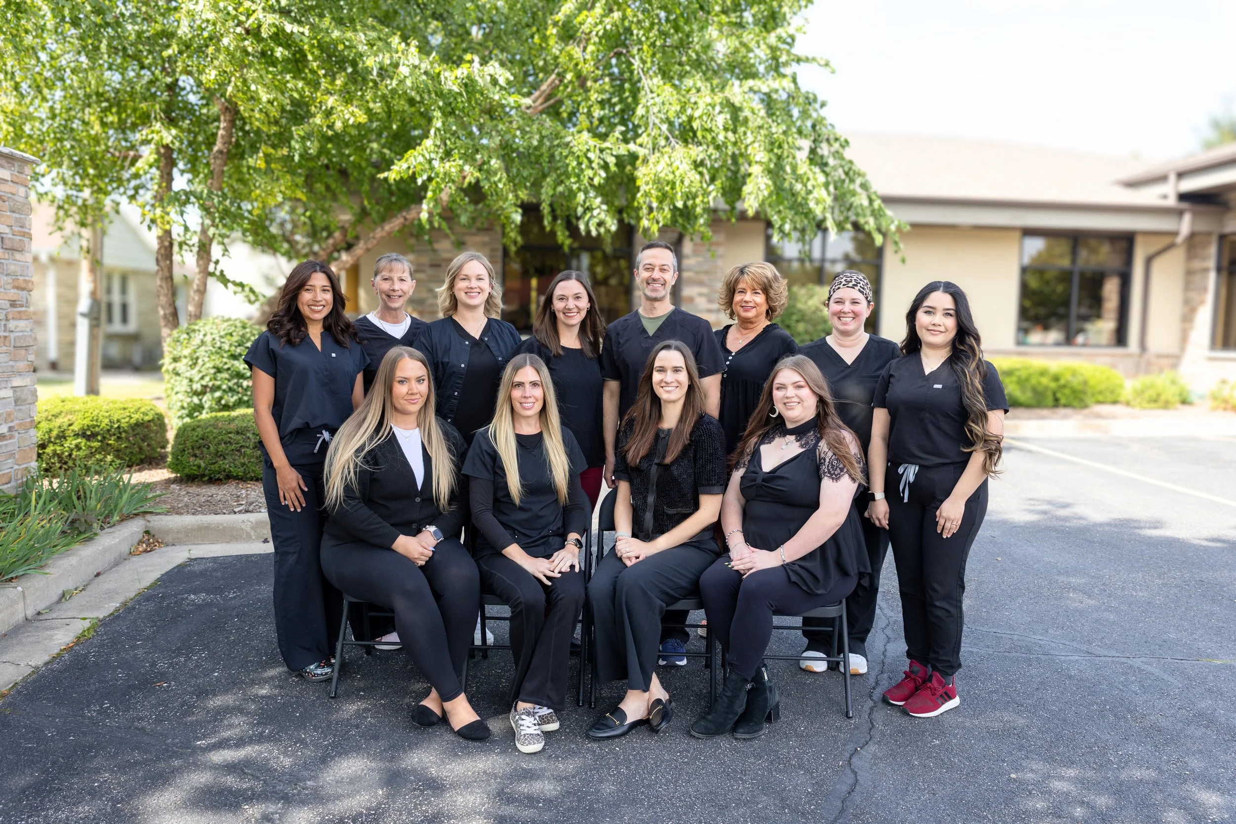 Greenfield Smiles team, mostly women, in scrubs posing outdoors in front of a house.