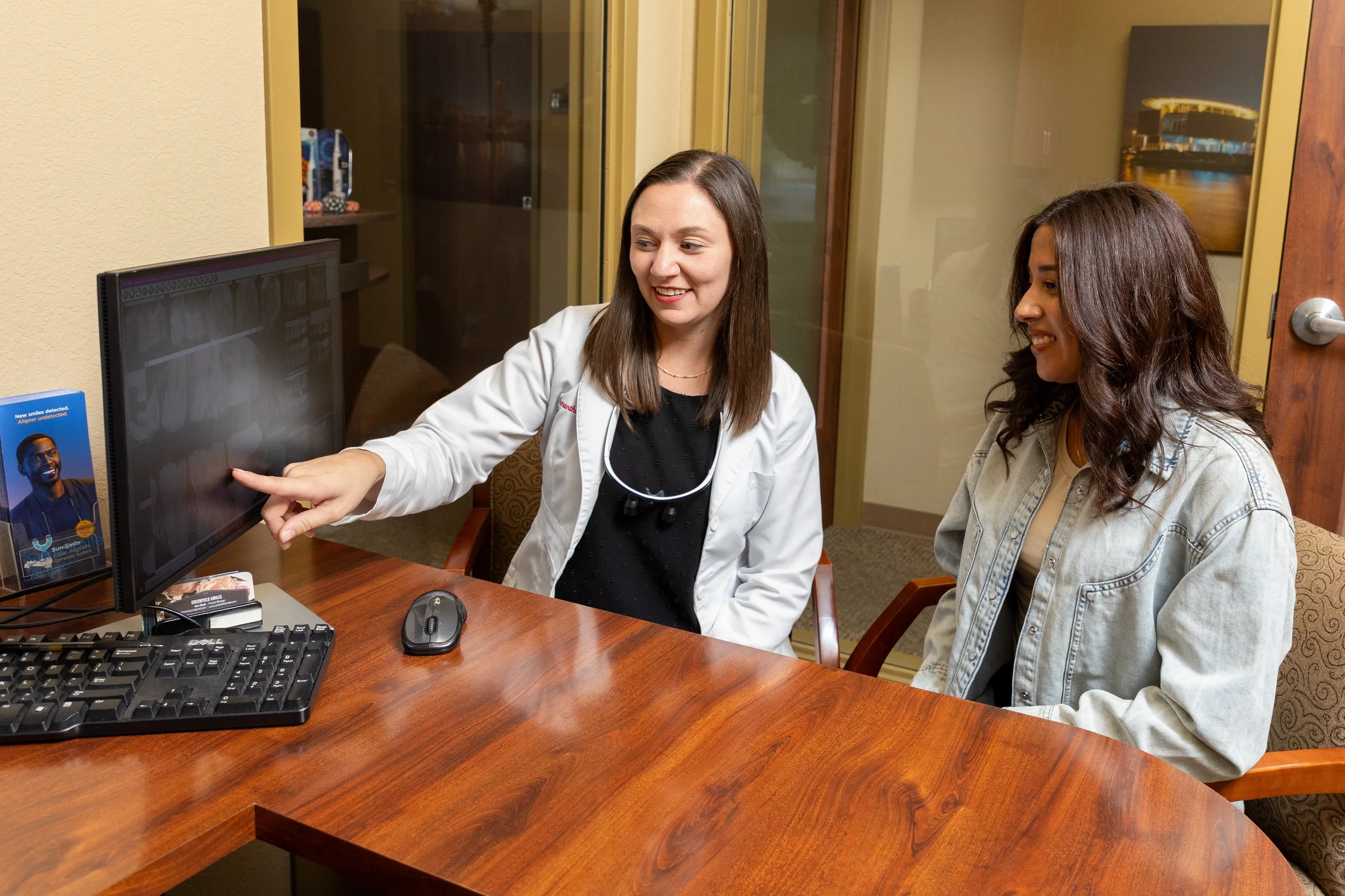 Medical professional showing an x-ray on a computer screen to a patient in an office setting.