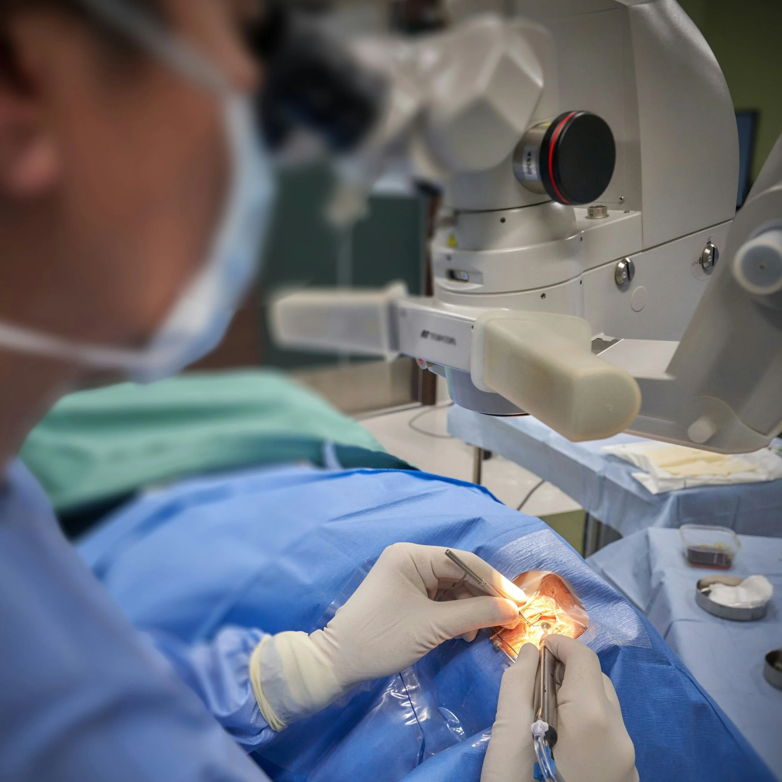 A surgeon performing a procedure with a microscope in a sterile operating room.