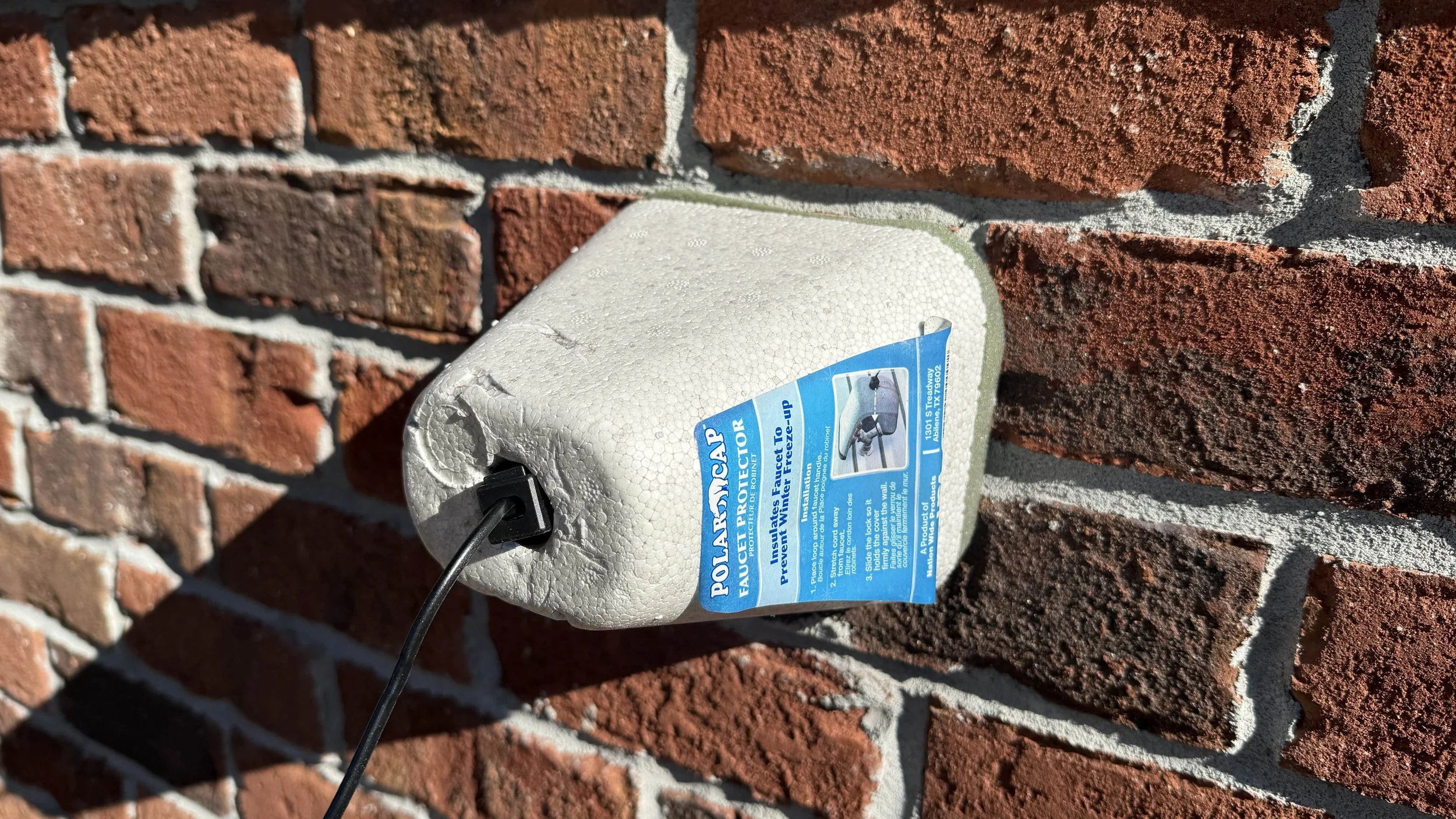 Hose Bib Faucet Protector with foam gasket on red brick wall