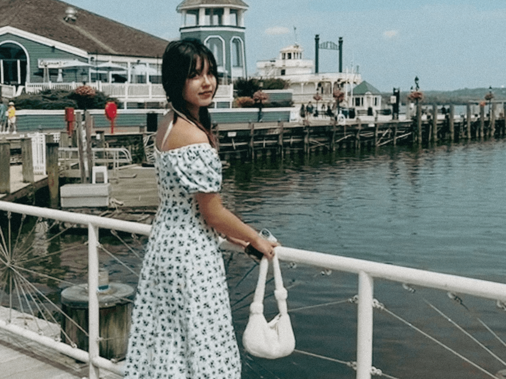 Elle stands at a harbor.