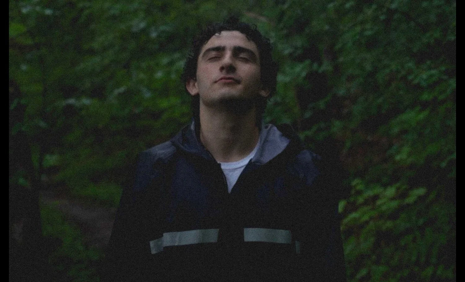 Yaakov Ellis looks up at the camera with his eyes closed.