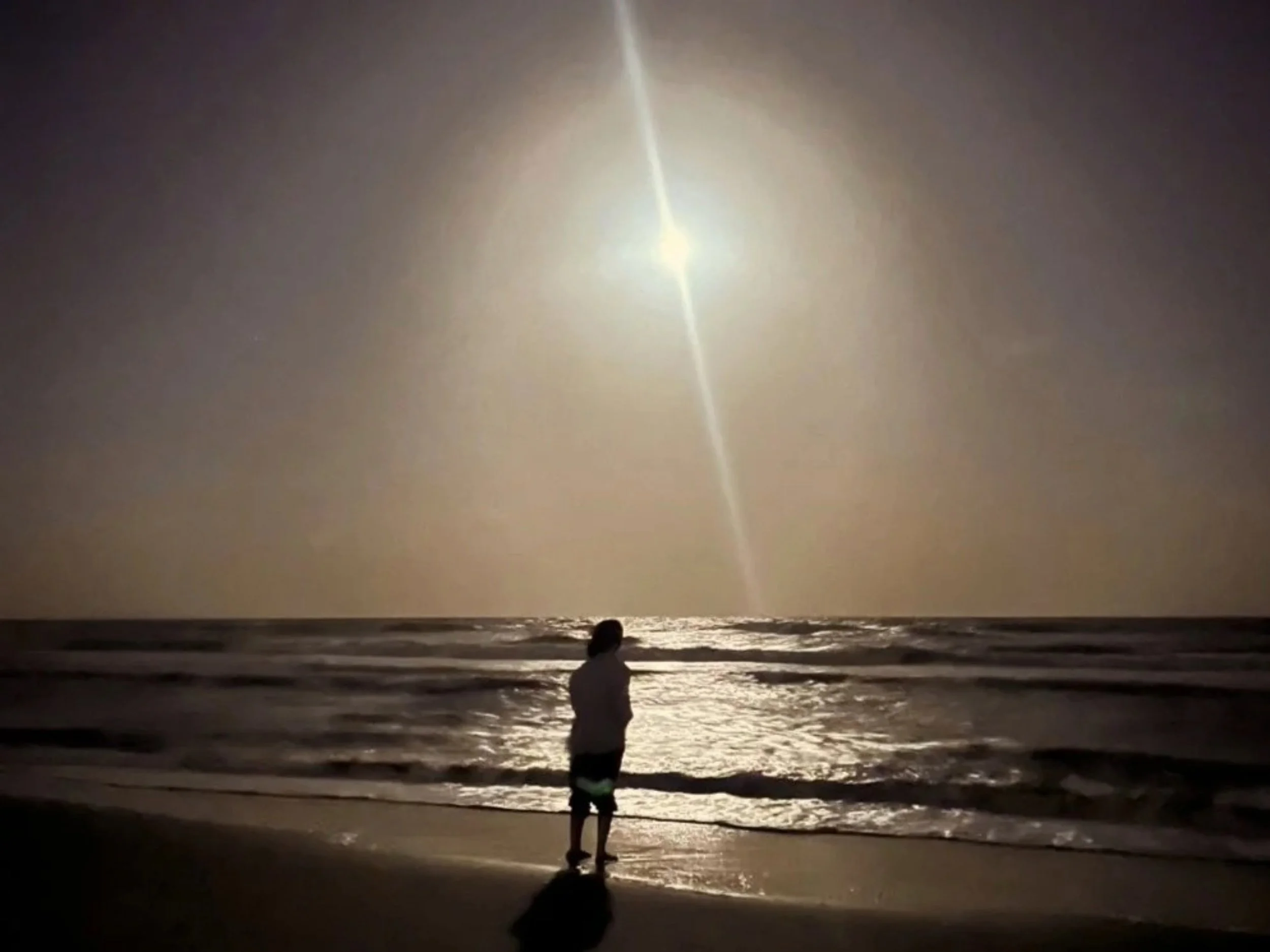 Lucie Vidh stands before the breaking water of a beach.