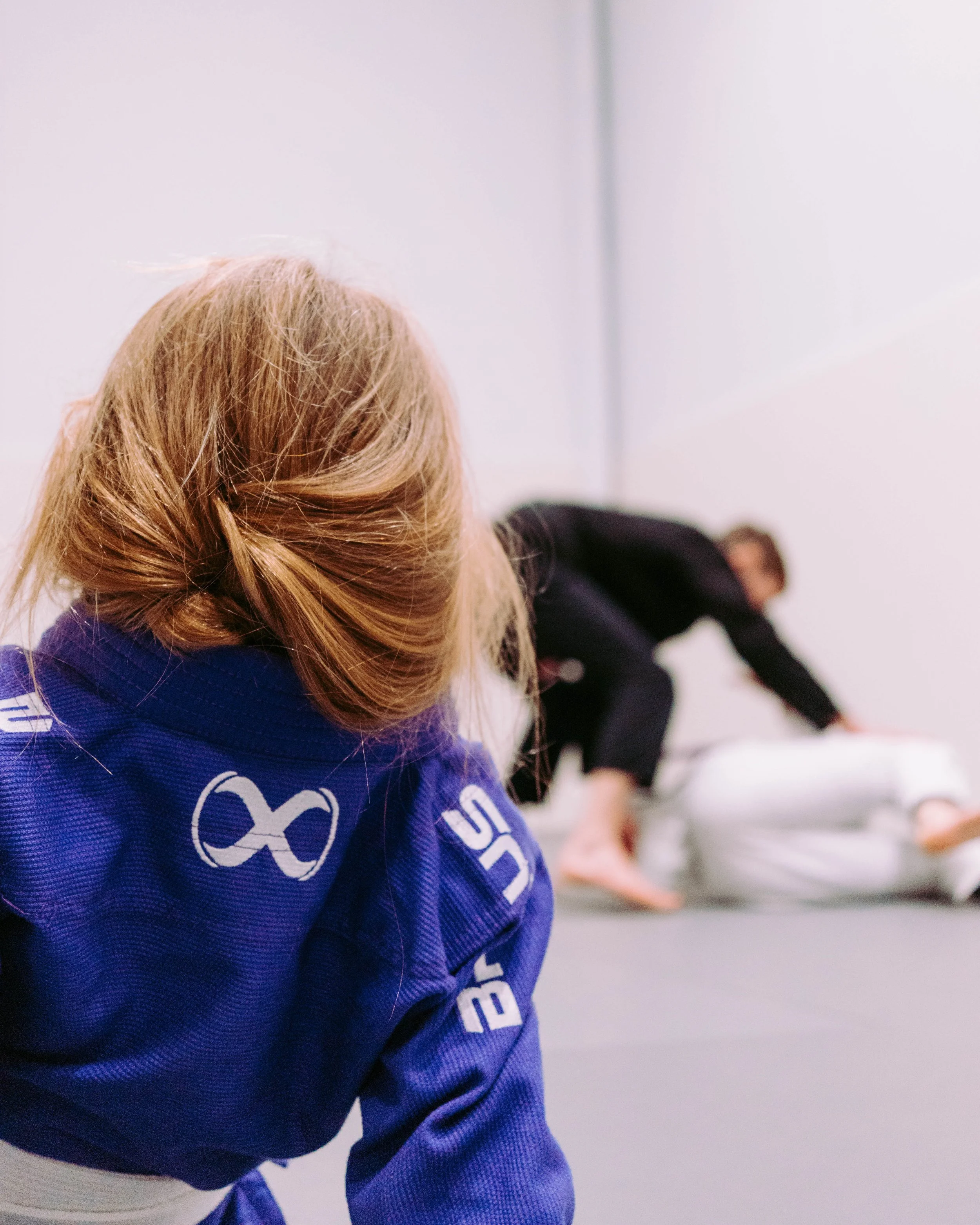 A young member watches two adults sparring on the mats at Melbourne Grappling Academy, Moorabbin