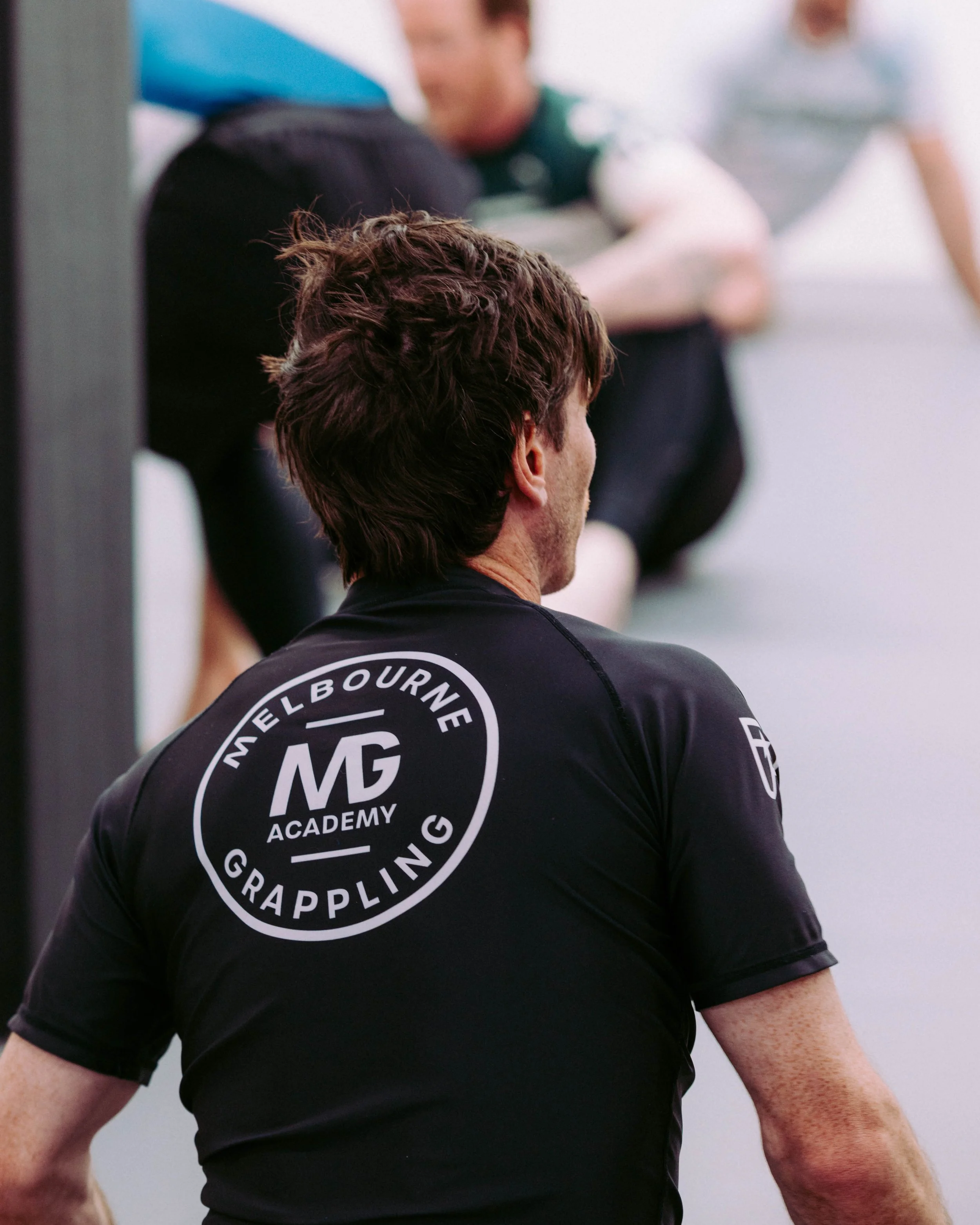 Member wearing a Melbourne Grappling Academy rash guard with the MGA logo on the back