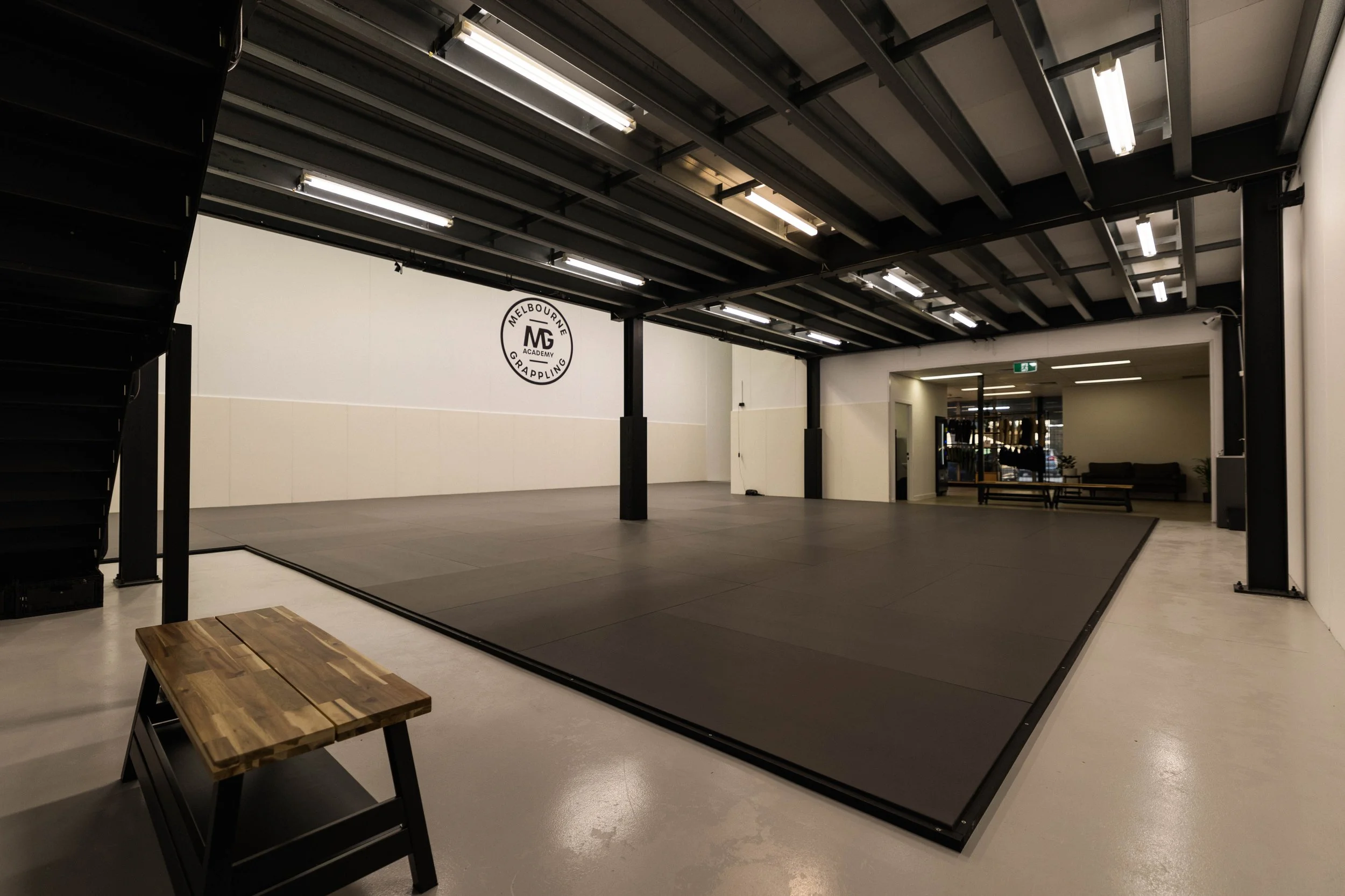 Wide angle view of the grappling mat space at Melbourne Grappling Academy, with reception and lounge in the background