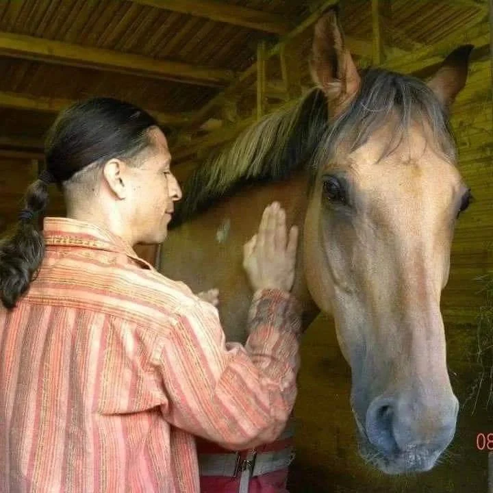 A woman petting a horse inside a wooden stable.
