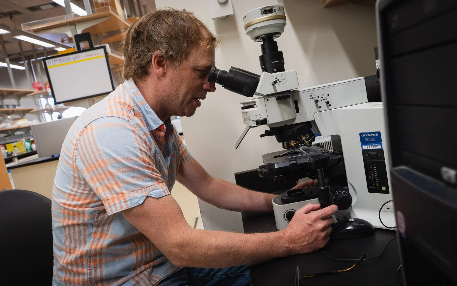  Sam Van de Velde uses a laboratory microscope that takes basic images of cells. (Photo by Thomas Murphy/Times of San Diego)  