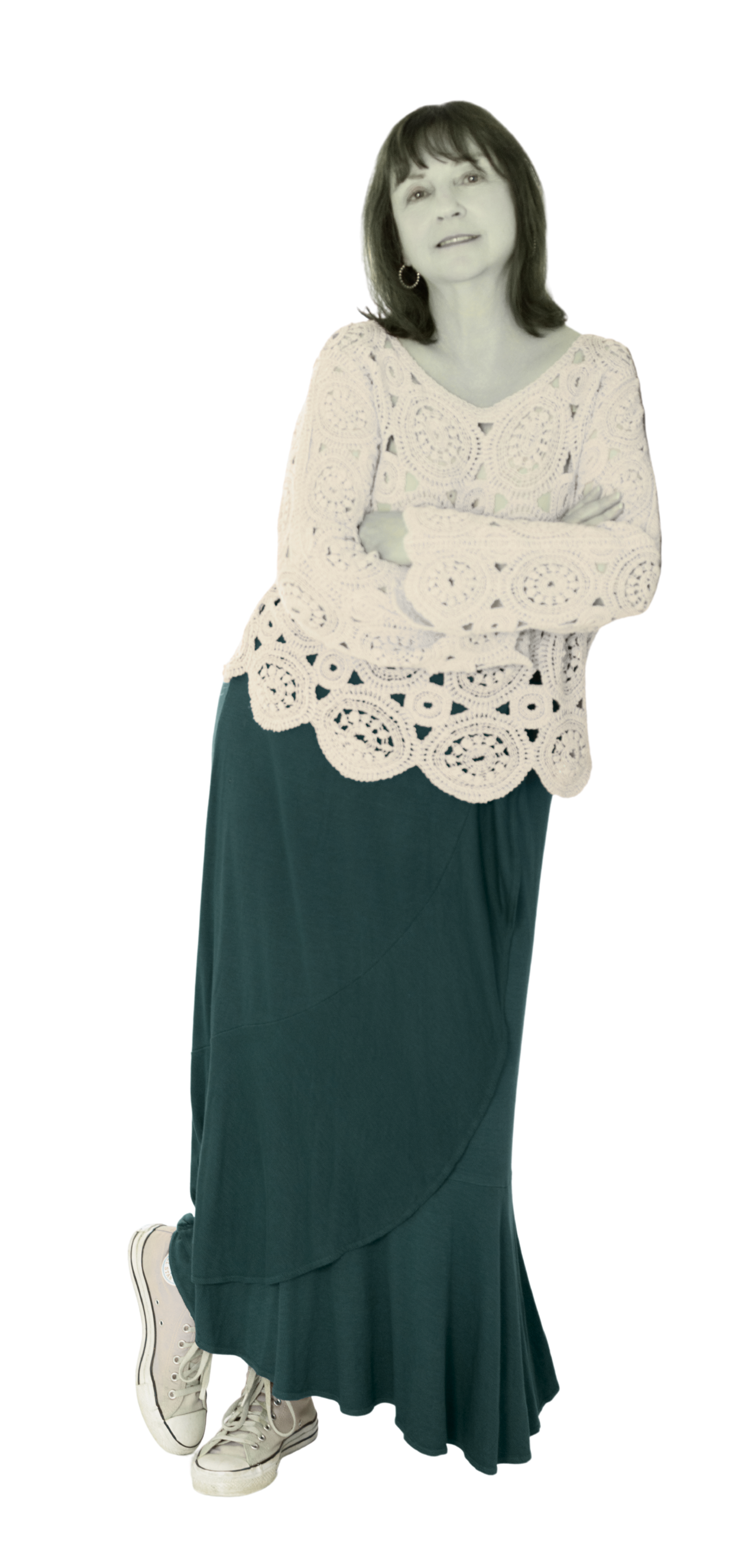 Susan Saint-Rossy standing with crossed arms wearing a crochet top, a long dark skirt, pink Converse sneakers, and hoop earrings.