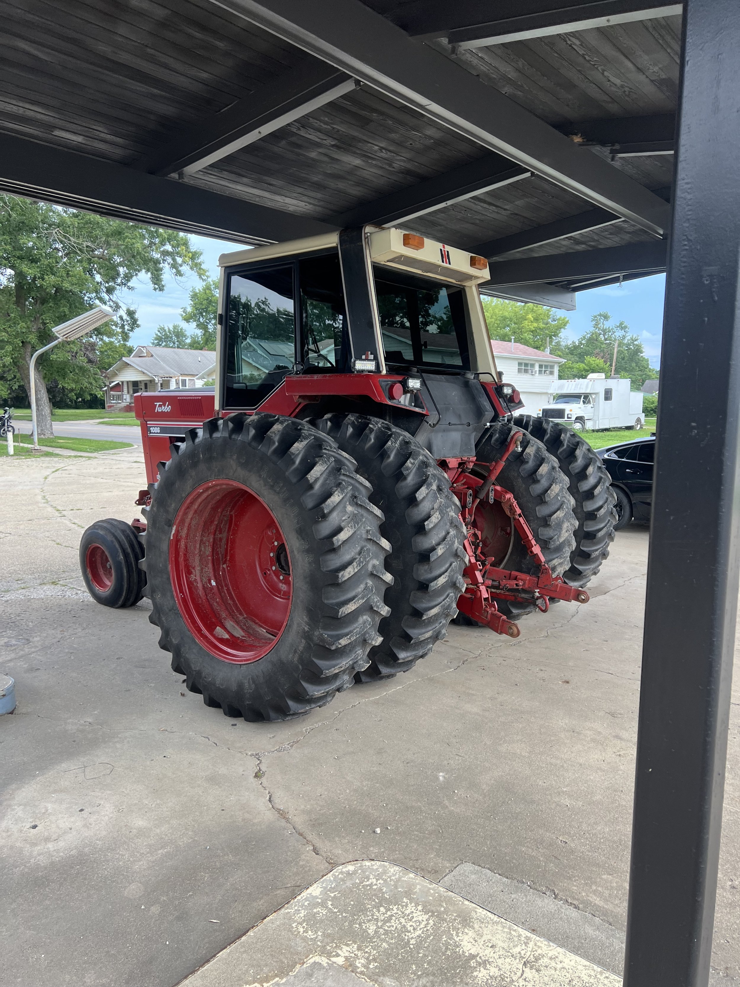 Red and black tractor parked under a carport.