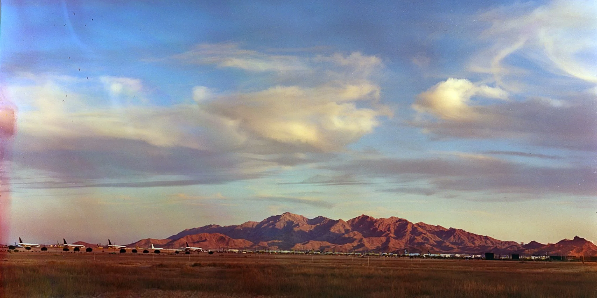 "Tarmac Horizon": Estrella Mountain rises in majestic contrast to the long line of grounded aircraft that stretch across the horizon. This juxtaposes the permanence of the natural landscape with the transience of human activity. This photo reflects