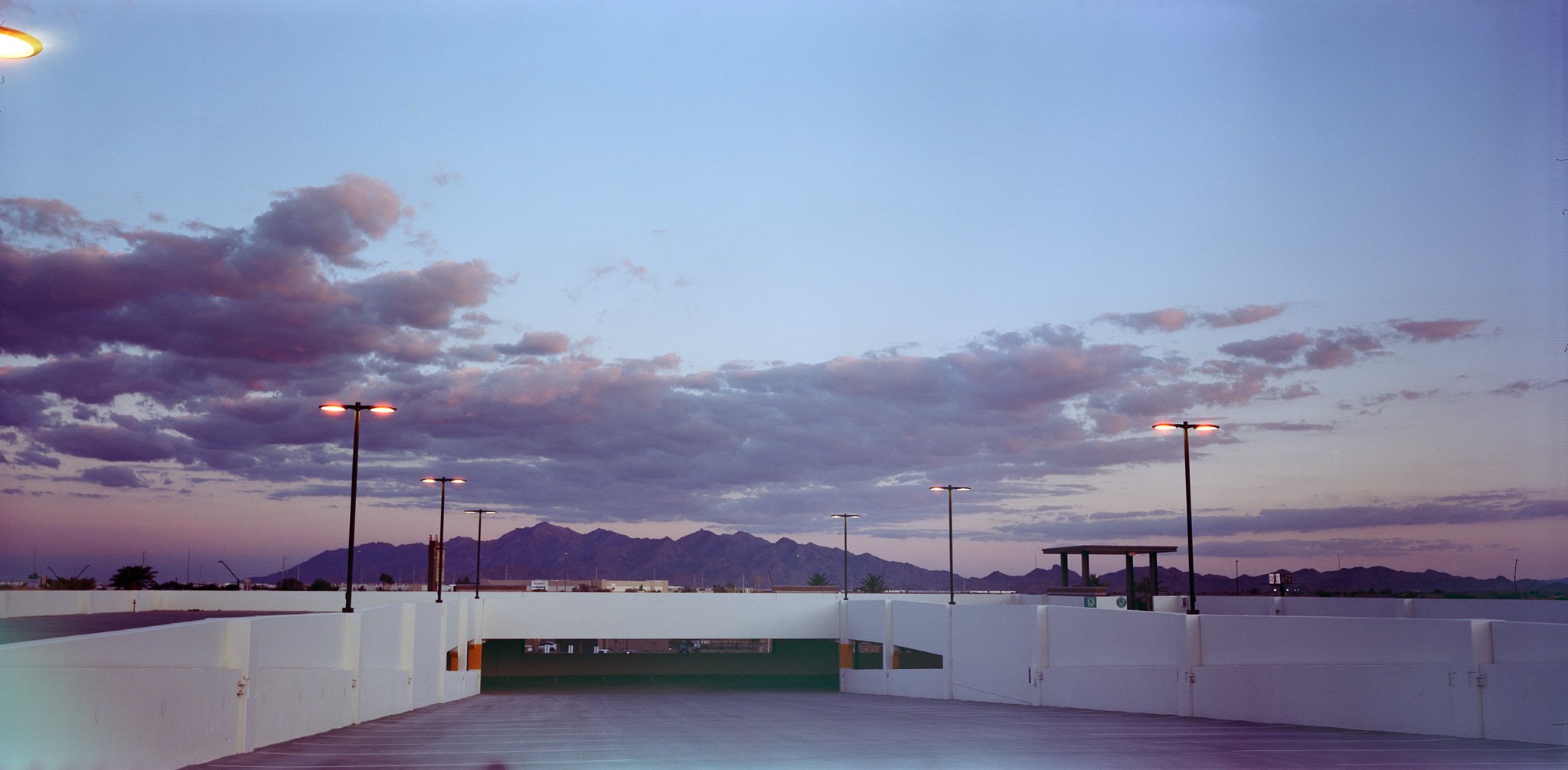 "Elevated Entry": the soft wash of a fading sunset, glowing lamps and the architectural lines all contribute to a surreal tension between the built environment and the natural one—suggesting that our access to nature is increasingly structured, elev