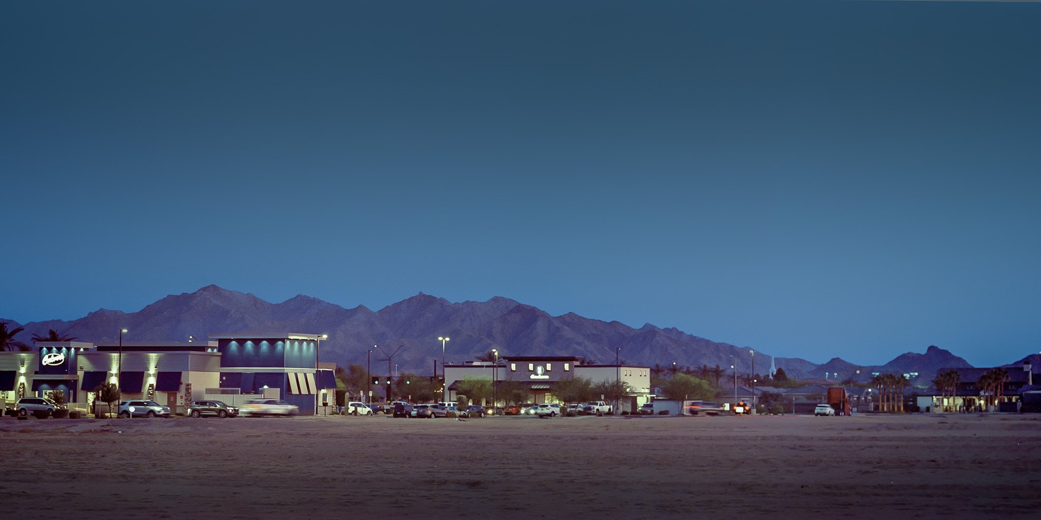 "Blue Hour Obscura: At twilight": the glow of a fast-food chain creates a veil between the viewer and the mountain. This speaks to how even the most grand and enduring landmarks can be eclipsed by the conveniences of modern development. In Finding E
