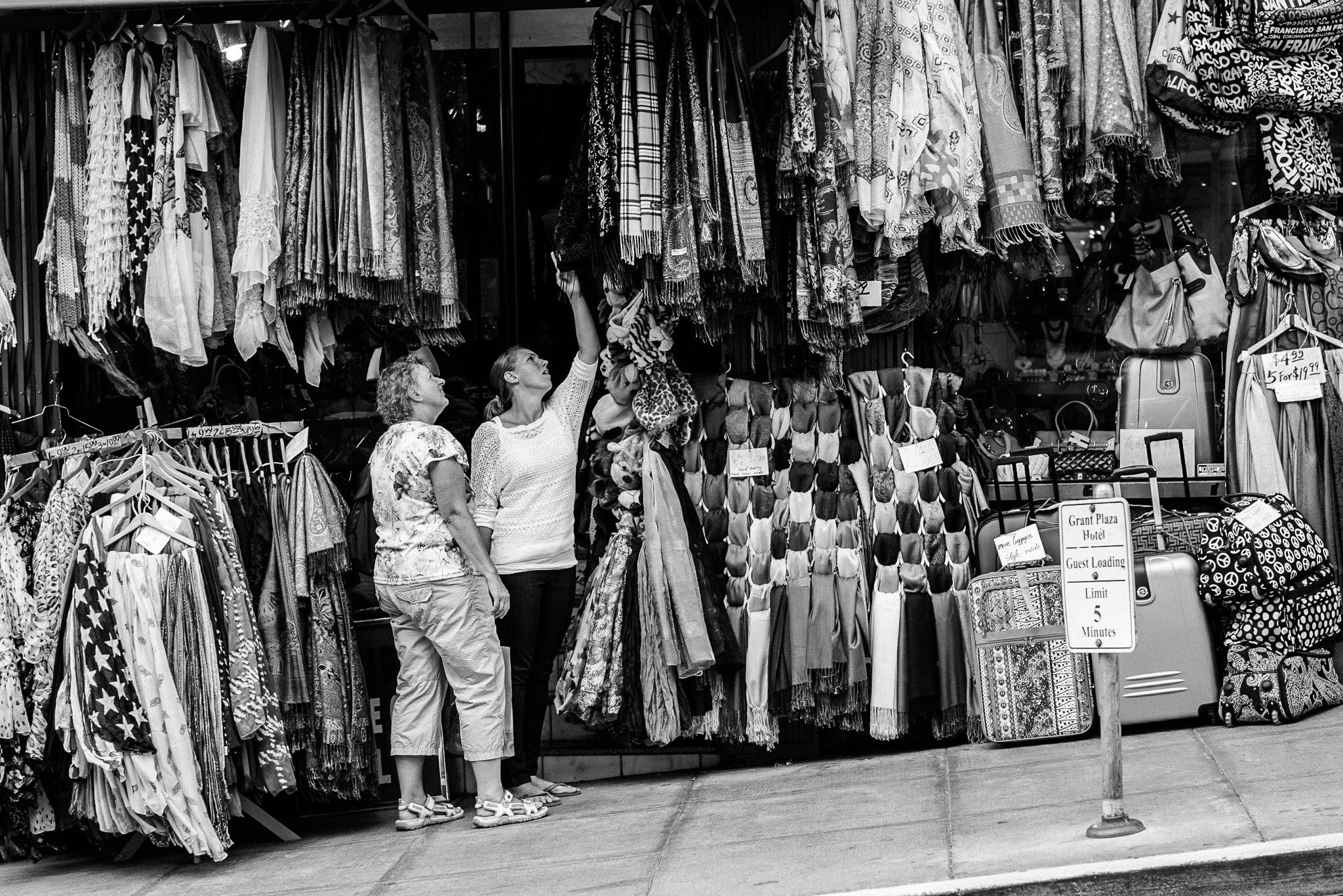 "The Reach" In a storefront bursting with pattern and color, two women reach, consider, and chat. The moment is small, familiar—part of the city’s daily rhythm. In The City, connection often happens in the simplest exchanges, woven into fabric, conve