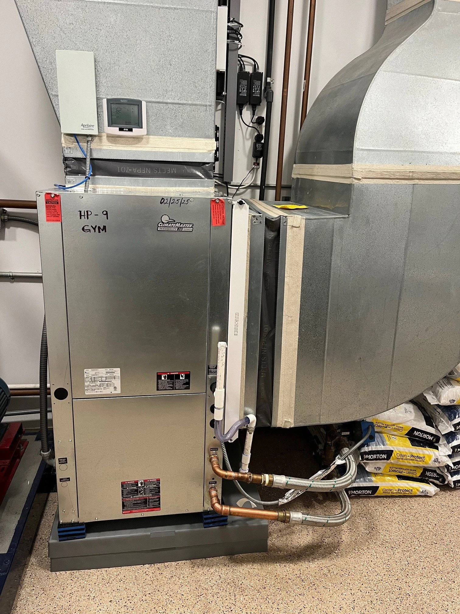 HVAC water source heat pump unit with connecting ducts, pipes, and electronic controls in a mechanical room.