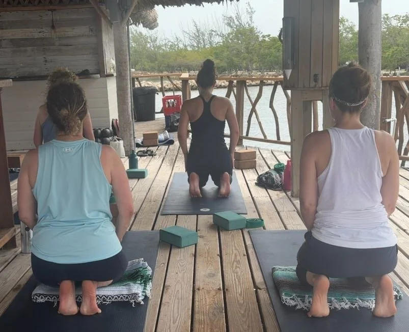 Members of yoga class in Hero Pose with foot stretch 