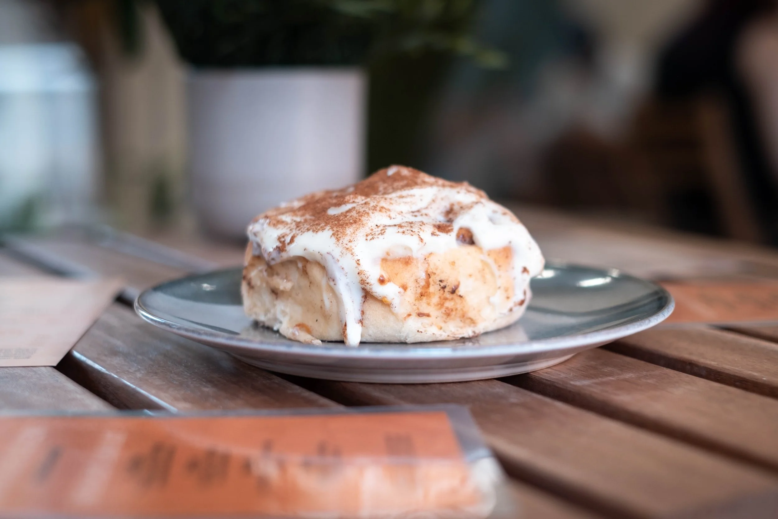 A dessert topped with whipped cream and sprinkled with cinnamon on a plate, placed on a wooden table.