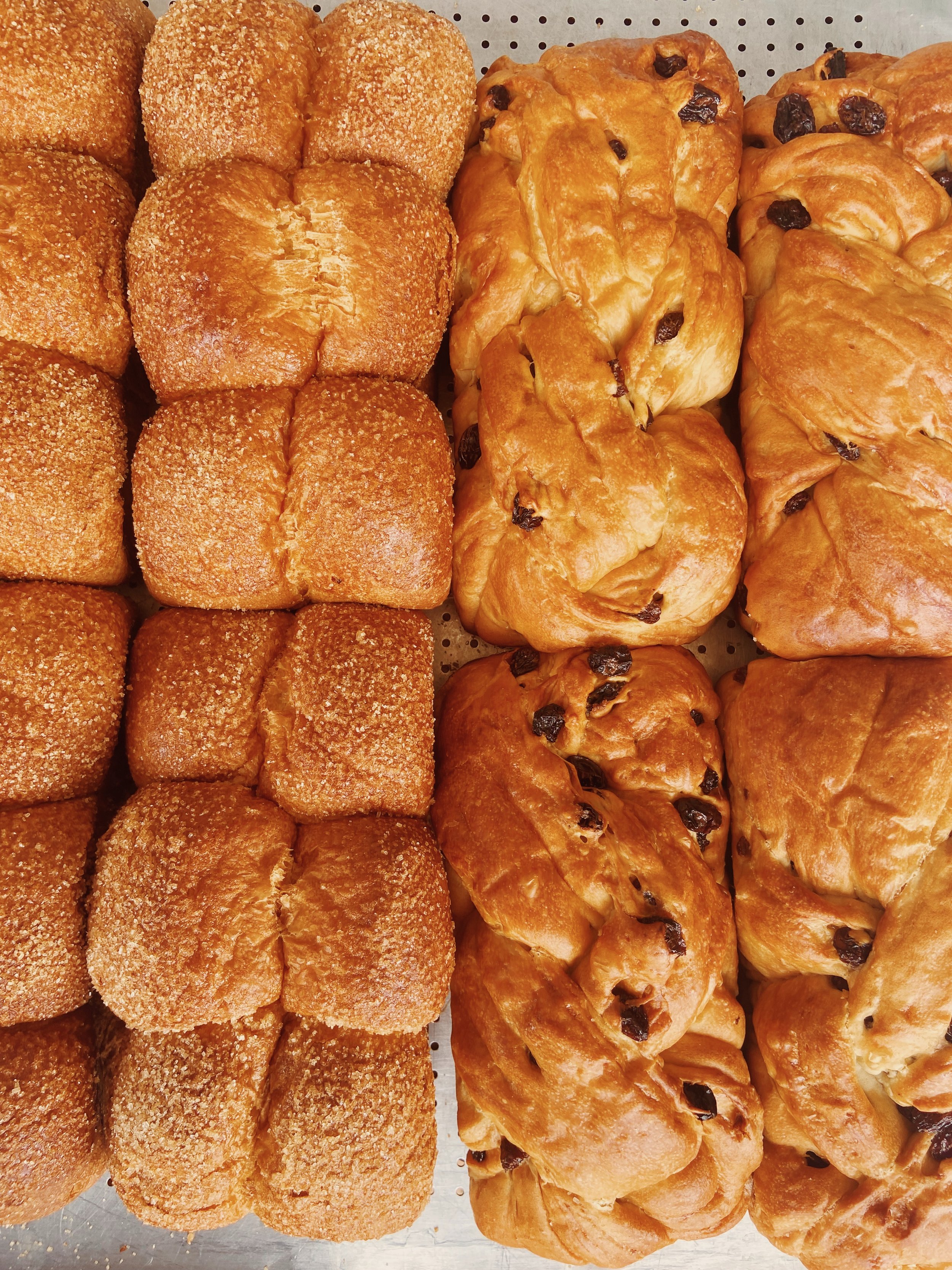 Assorted baked goods including sugar-coated bread rolls on the left and chocolate croissants on the right.
