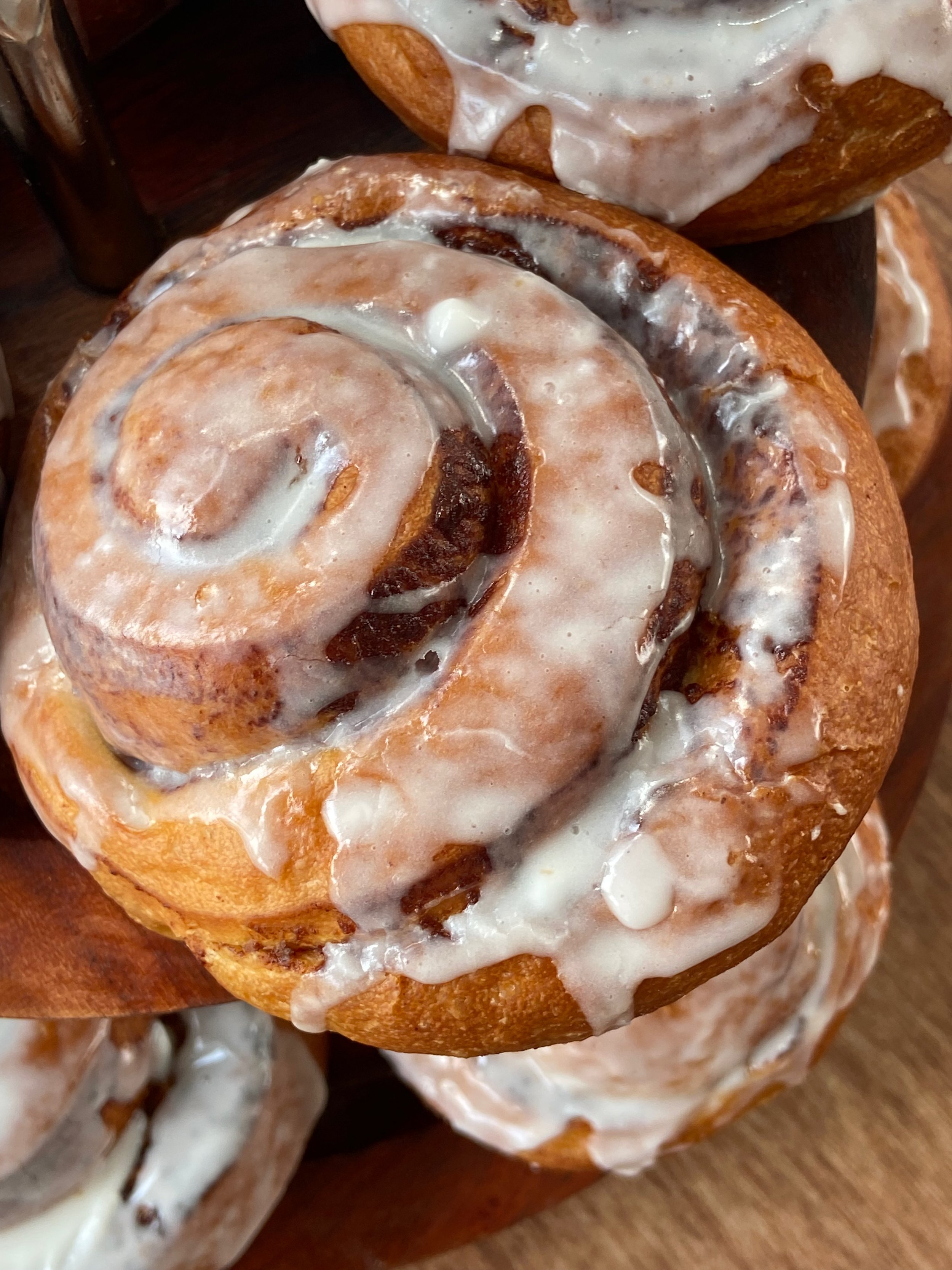 Close-up of a cinnamon roll with icing on top, showcasing the swirled shape and golden-brown crust.