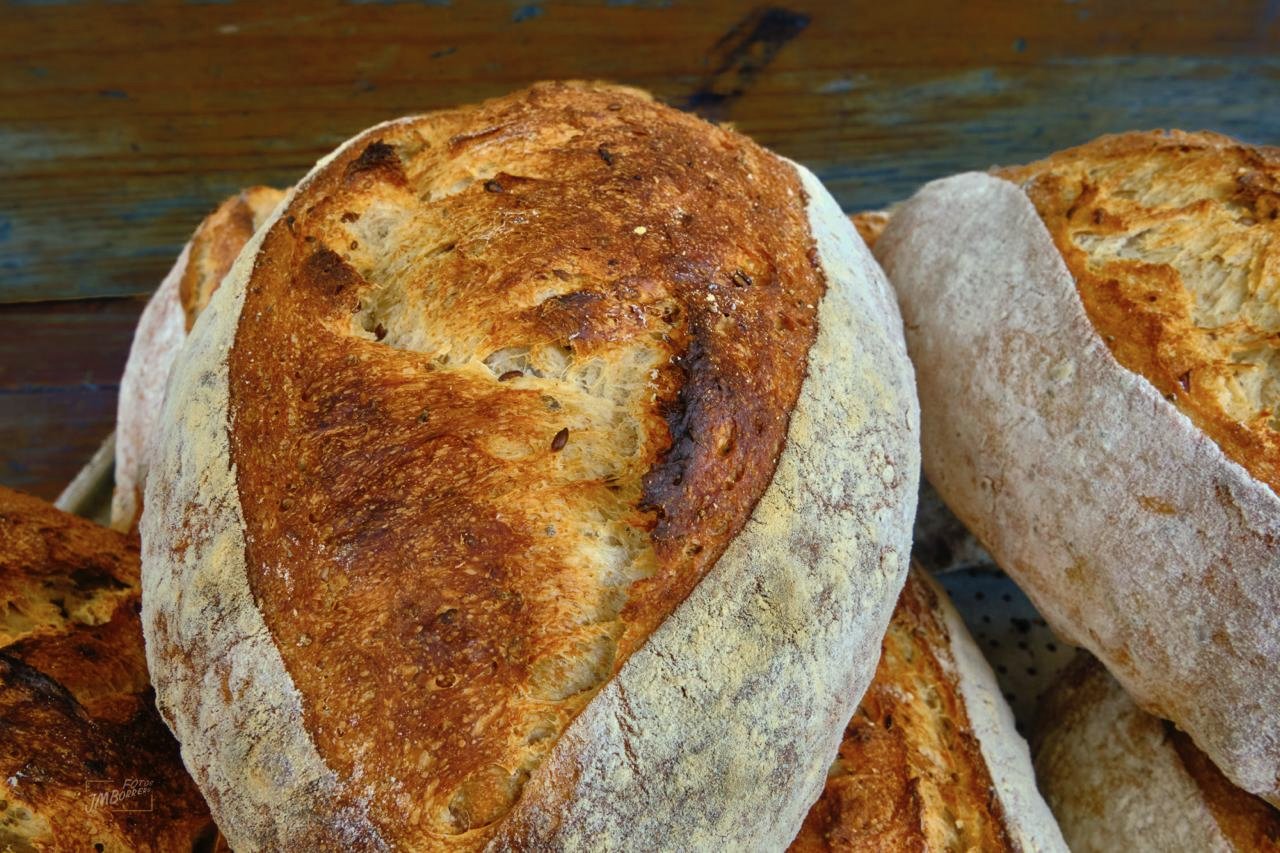 Close-up of freshly baked rustic loaves of bread with a golden-brown crust on a wooden surface.