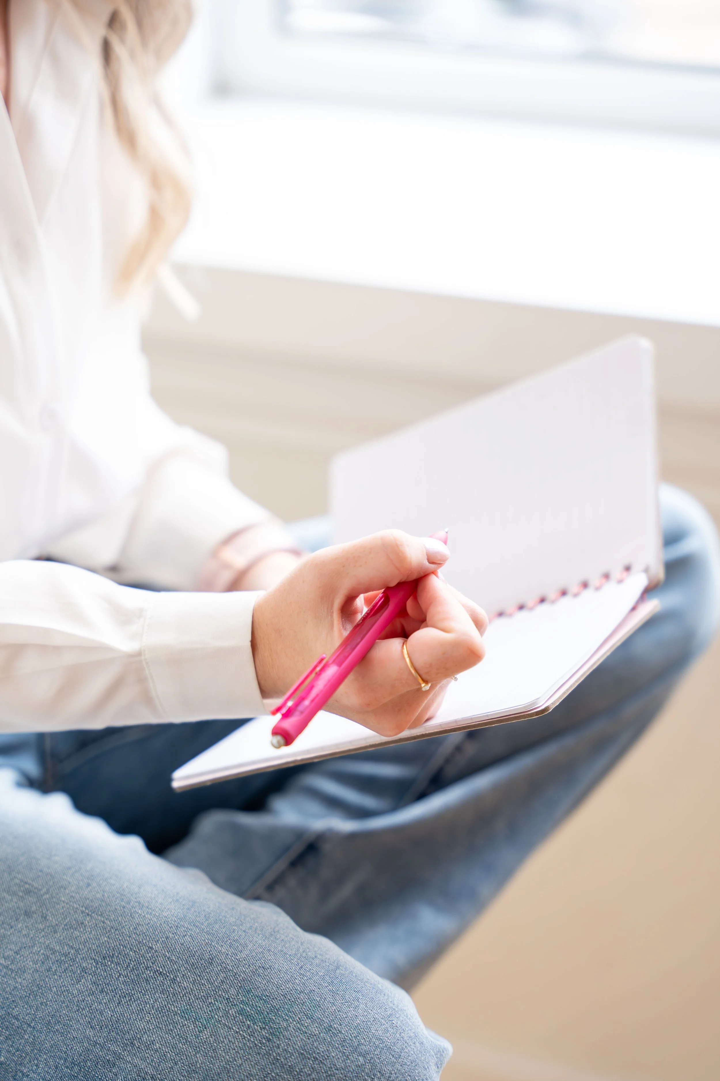 Person taking notes with a pink pen inside a notebook