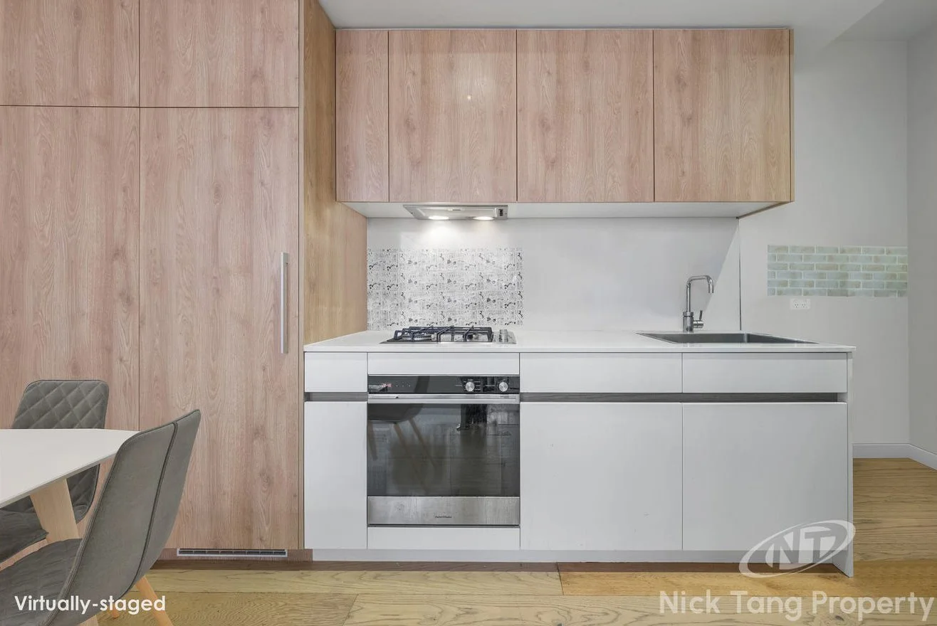 Kitchen with light wood cabinets, white countertop, and built-in oven, small tiled backsplash, and a black sink with a chrome faucet.