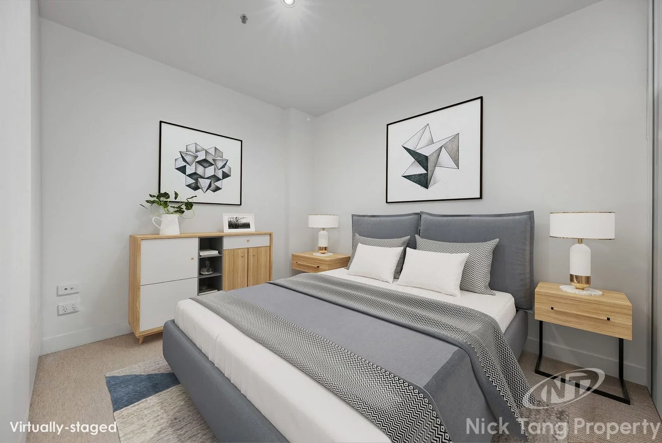Modern bedroom with a bed, gray upholstered headboard, white and patterned pillows, two wooden nightstands with lamps, a sideboard with a potted plant and picture, and geometric framed artwork on white walls.