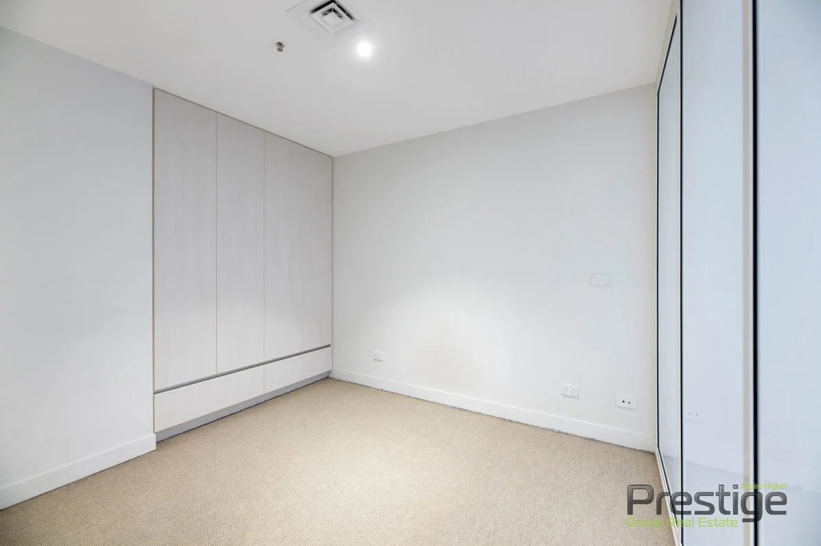 Empty room with beige carpet, white walls, two white closet doors, and a glass sliding door closet on the right