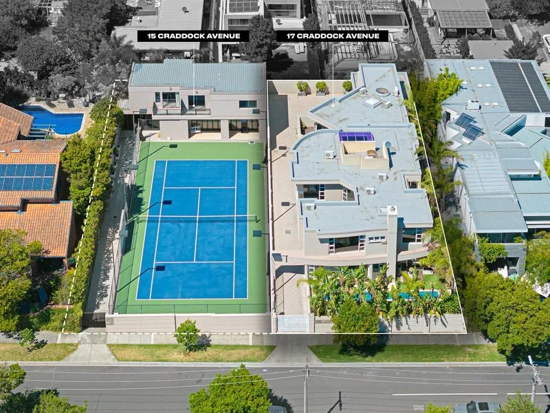 Aerial view of a residential area showing a modern house with a rooftop pool, a basketball/tennis court, and neighboring houses along a street.
