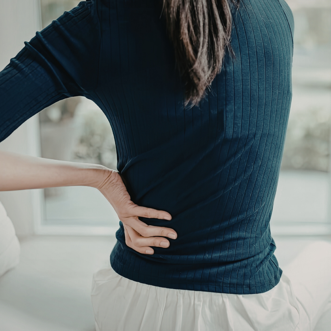 A woman holding her back like she is in pain