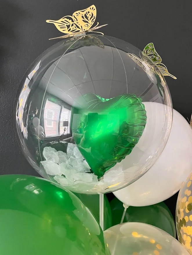 Stuffed bubble balloon with white flower petals, green foil heart and gold butterflies
