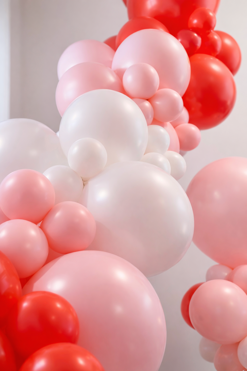 Blush, white, and red balloon garland for event backdrop