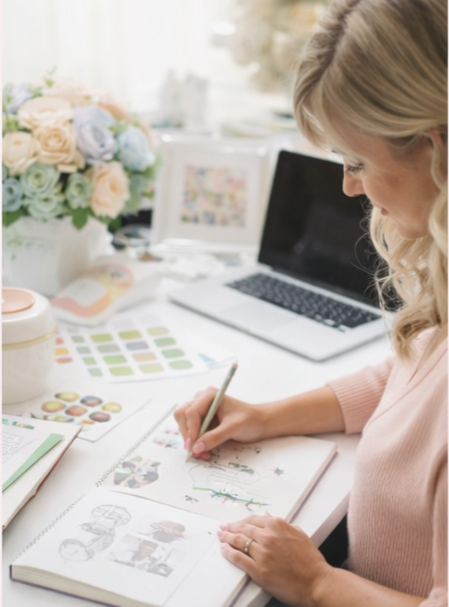 Woman sitting at a desk with a notebook, planner, and laptop