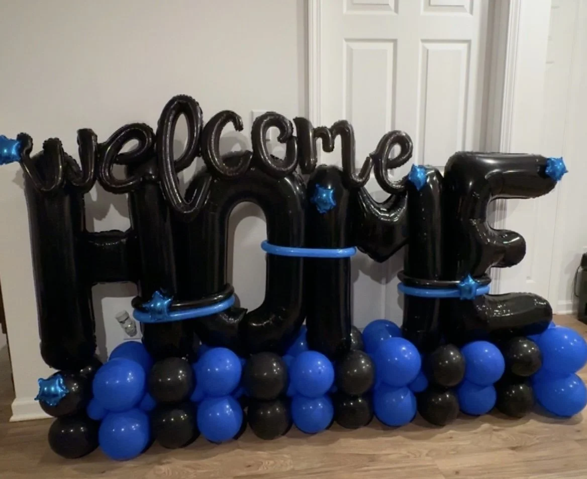 Welcome home balloon stack with black and blue balloons.