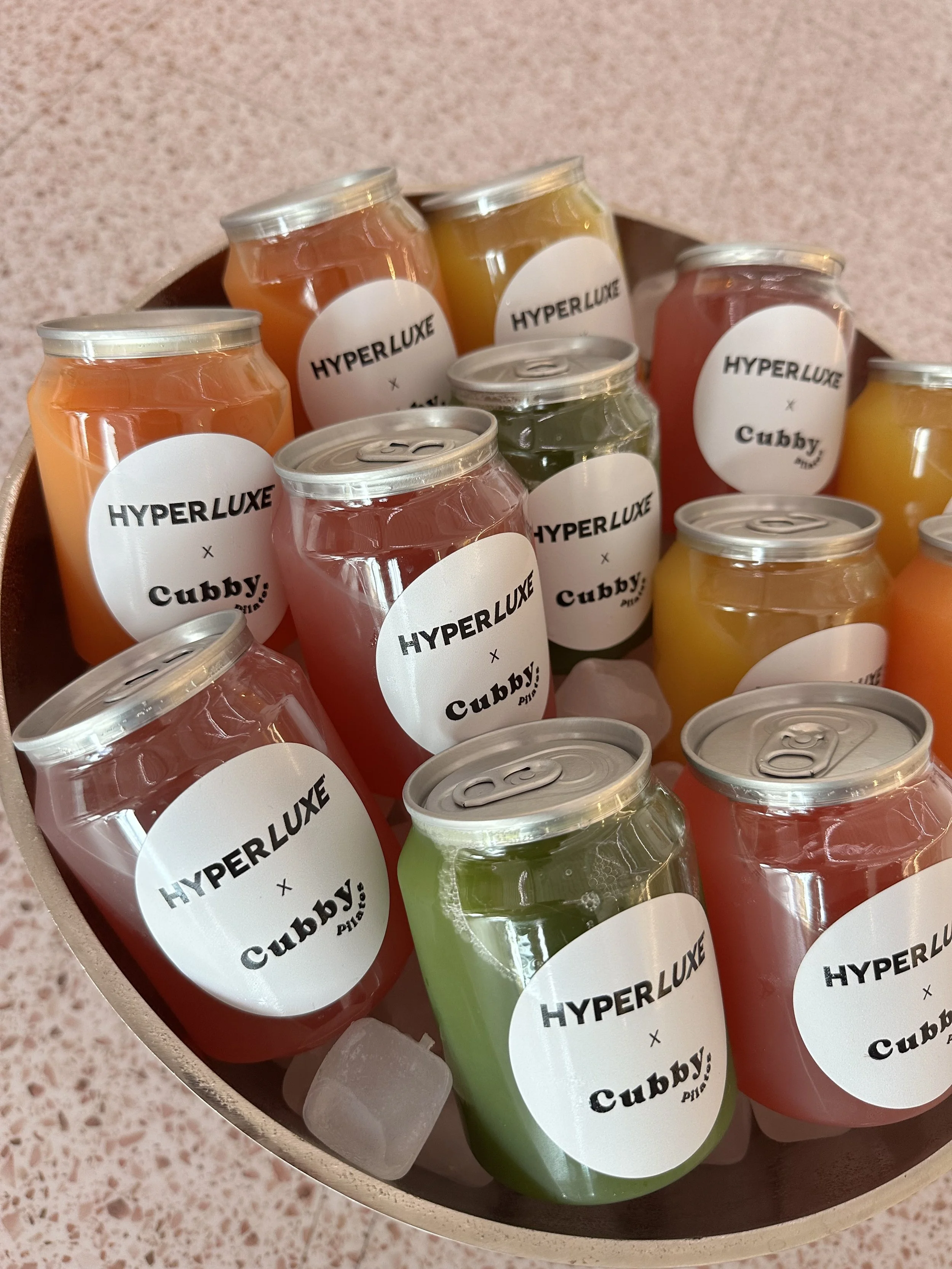 Assorted colorful canned beverages labeled 'Hyperluxe x Cubby '